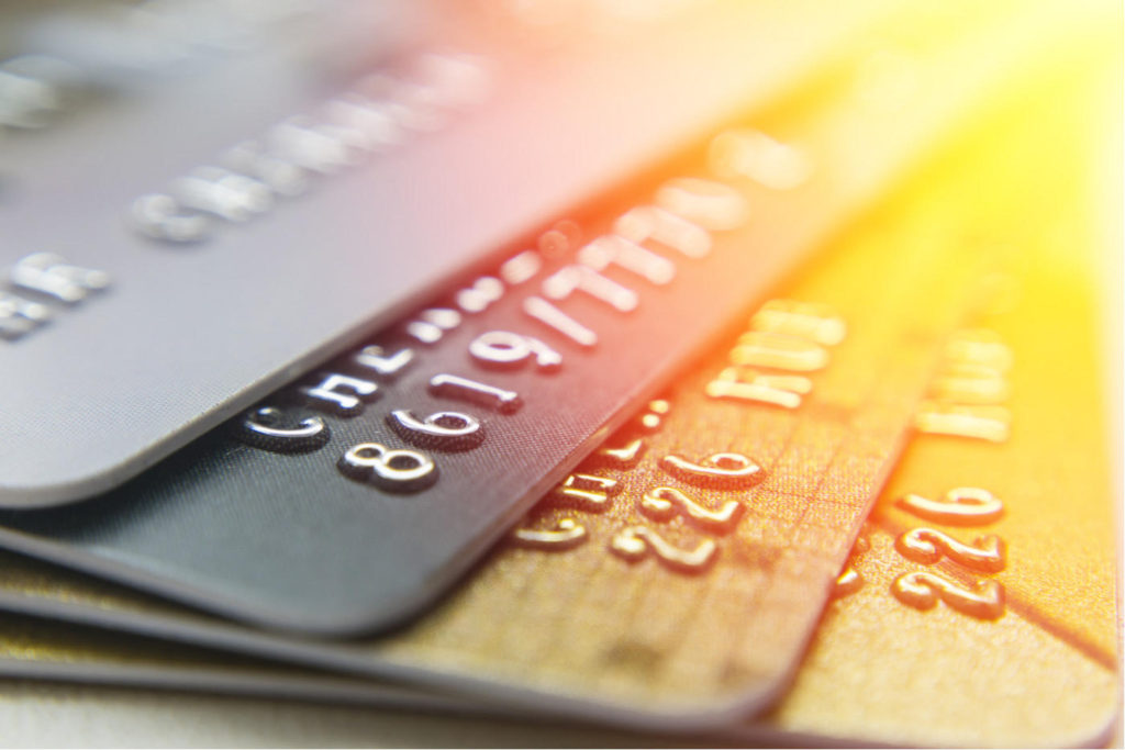 Bank cards for many different bank accounts lay on wooden surface (digital rendering)