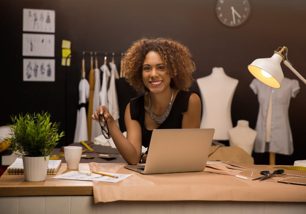 signs you're an entrepreneur: A young female Latino entrepreneur sits at her desk with a computer