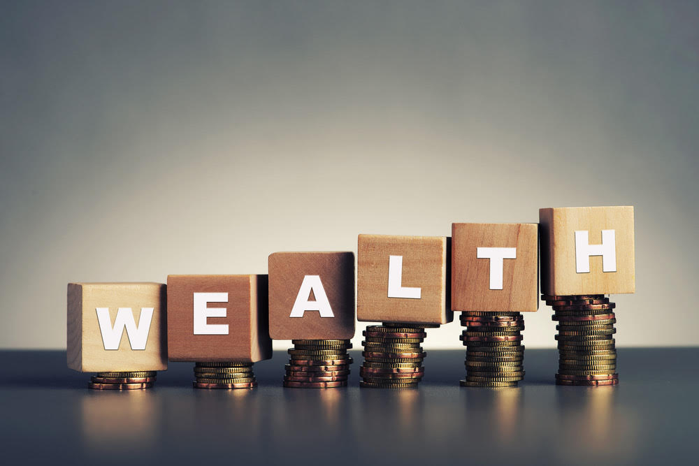 Build wealth: The word "Wealth" spelled out on wooden blocks, raised on pennies