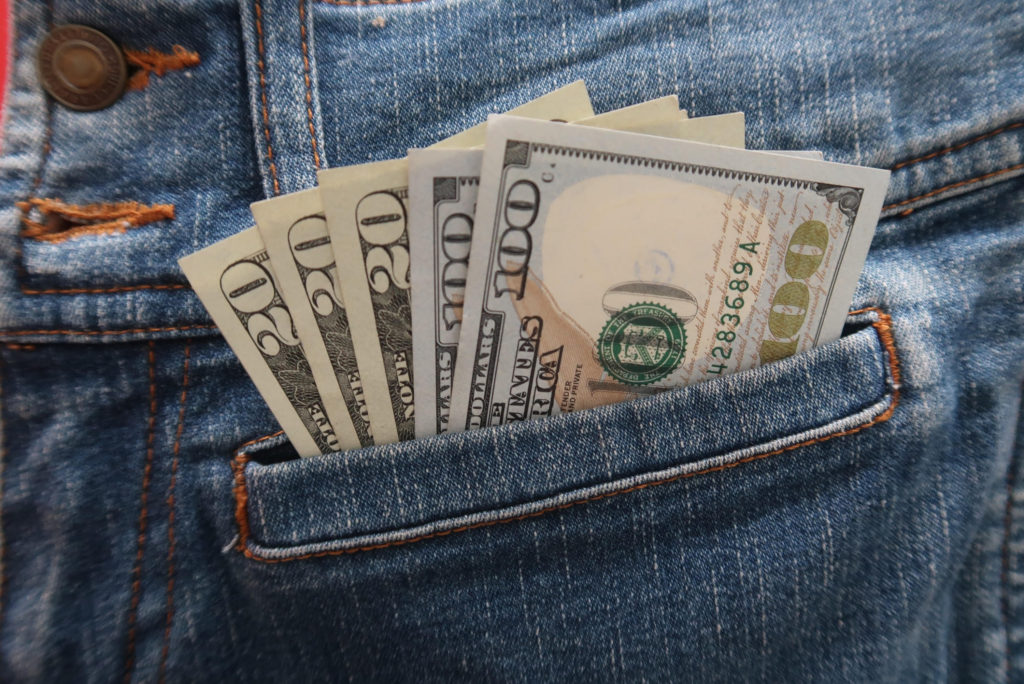side hustles for teens: a pair of blue jeans with two one hundred dollar bills and three twenty dollar bills in the pocket 