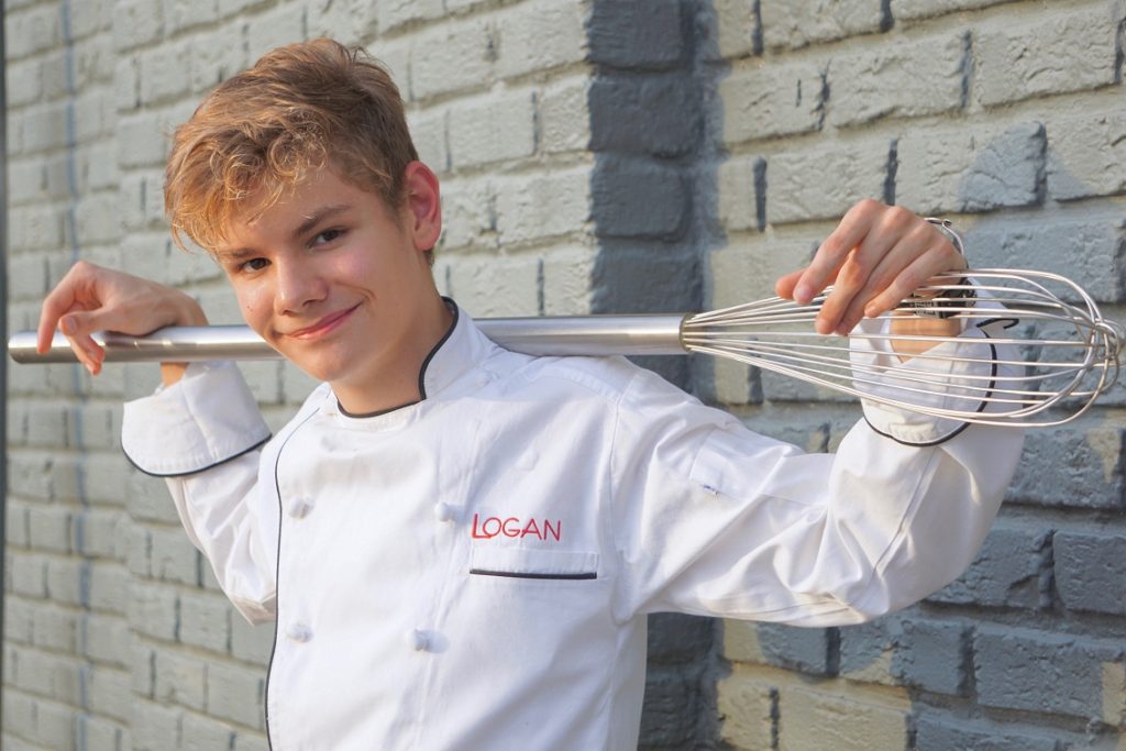 Logan Guleff: a young kid stands with a large spatula for a photo op.