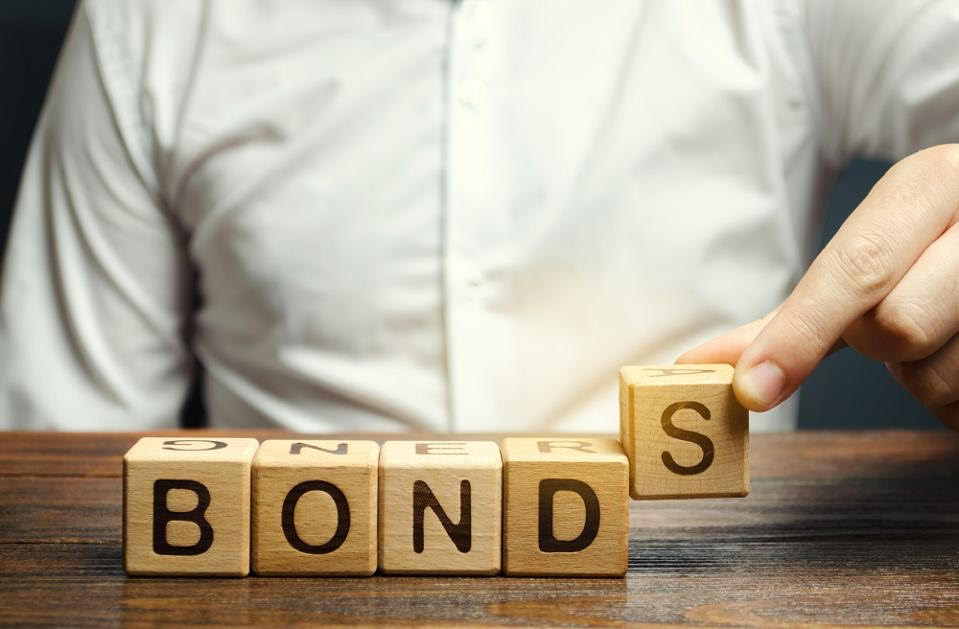 Types of bonds: a man in a white shirt adding wooden blocks that read the word "Bonds"