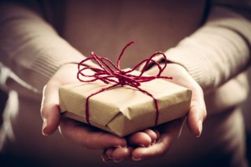 Best gifts for entrepreneurs: two hands passing a gift, packaged in retro packaging
