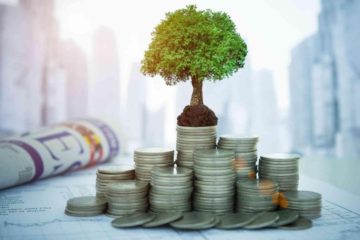 Safest investments: a pile of coins with a little tree growing with buildings, a newspaper and stock information in the background