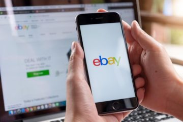 Most expensive things ever sold on eBay: a man logging in to eBay on his phone, with eBay open on his computer