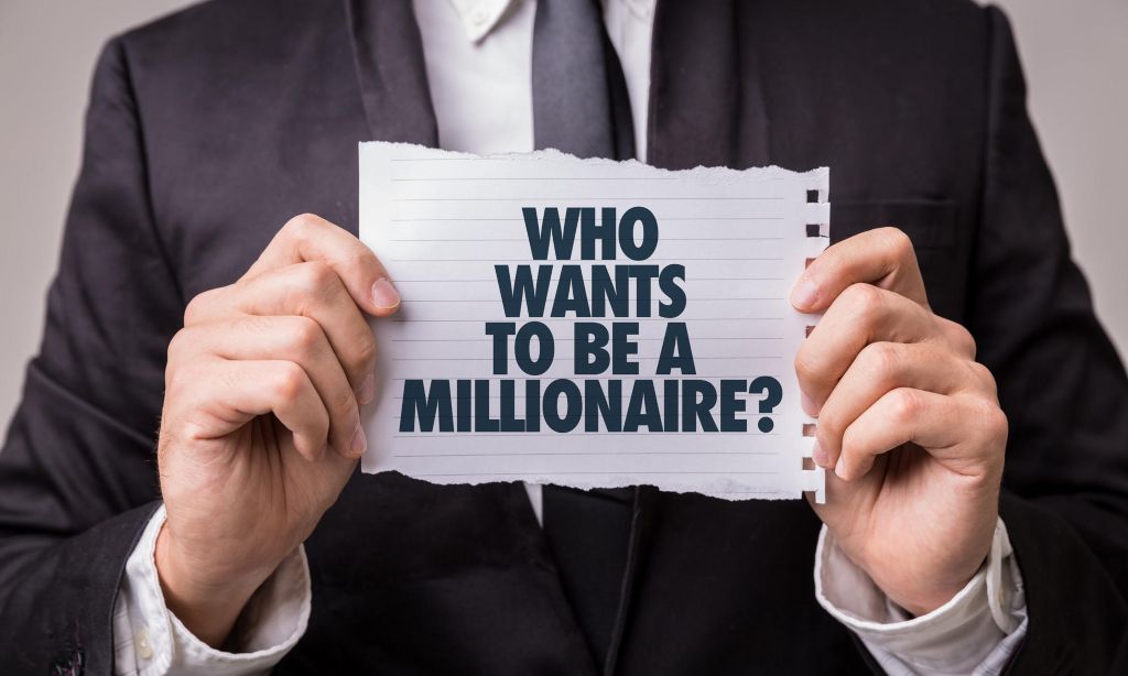 Best ways to become a millionaire: A man in a black suit holding up a piece of paper, reading: "Who wants to be a millionaire?" on it