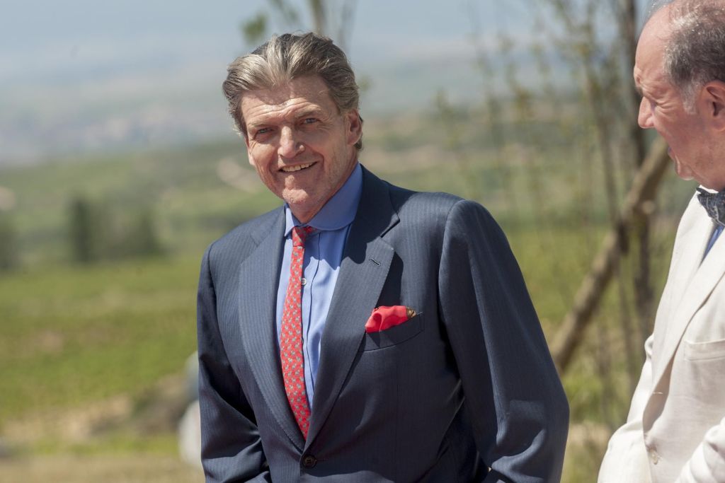 Benjamin de Rothschild wearing a suit and walking with Pablo Alvarez Mezquiriz with vineyards in the background