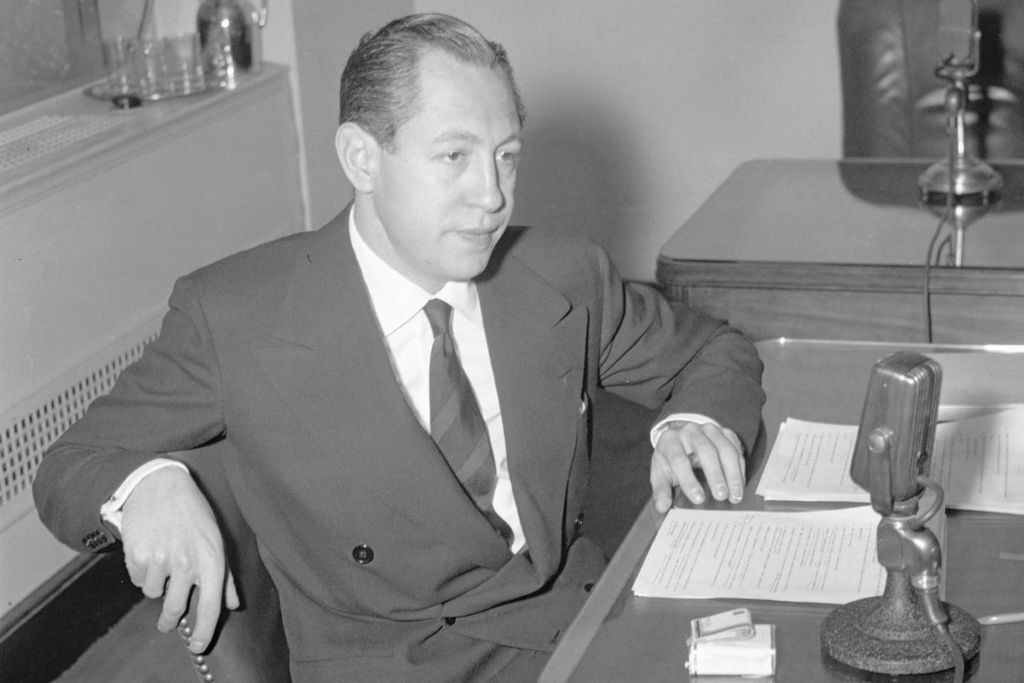 Cigar kingpin-turned media baron William S. Paley sitting at a desk in front of radio broadcasting equipment